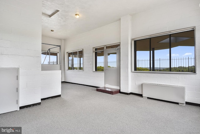 spare room featuring radiator heating unit and concrete block wall