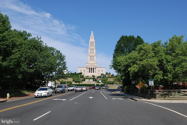 view of asphalt road featuring curbs and street lights