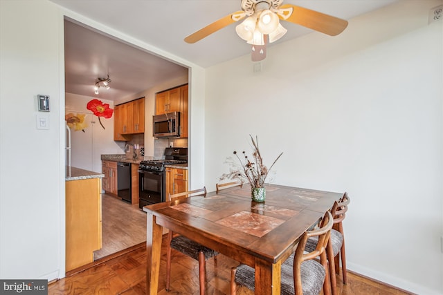 dining space with a ceiling fan, baseboards, and light wood-style flooring