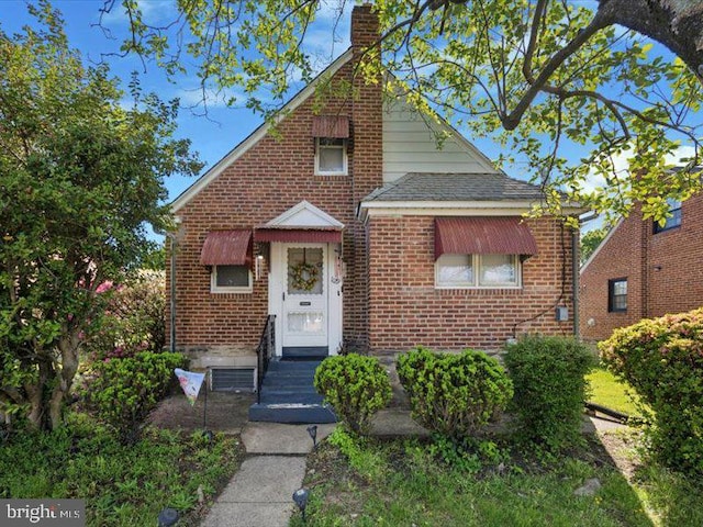 view of front of house with brick siding and a chimney
