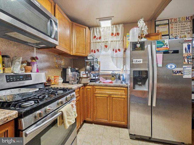 kitchen featuring appliances with stainless steel finishes, brown cabinets, and light tile patterned floors