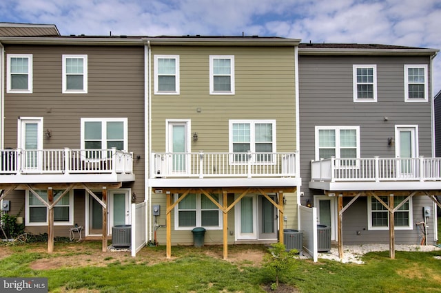 rear view of property with central AC unit and a yard