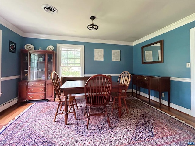 dining room with ornamental molding, wood finished floors, and baseboards