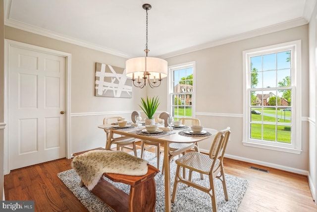 dining room with a chandelier, light wood-style floors, crown molding, and baseboards