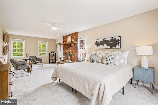 carpeted bedroom with baseboards, a brick fireplace, and a ceiling fan