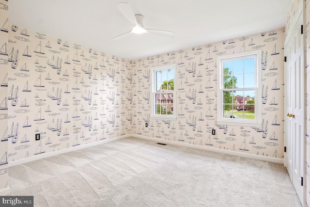 carpeted empty room with baseboards and a ceiling fan