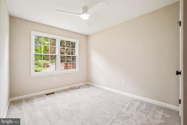 carpeted spare room featuring baseboards and a ceiling fan