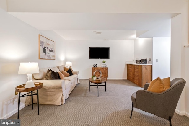 living area featuring light carpet and baseboards
