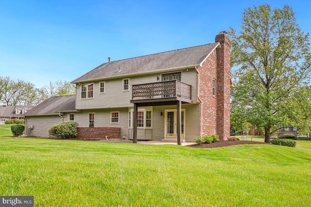 rear view of property with a chimney, a yard, and a balcony