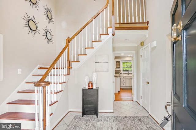 foyer entrance featuring stairs, tile patterned floors, crown molding, and baseboards