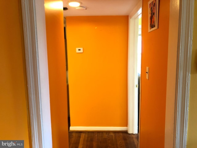 hallway with dark wood-type flooring and baseboards
