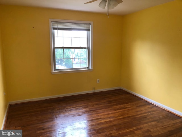 empty room featuring ceiling fan, dark wood-type flooring, and baseboards