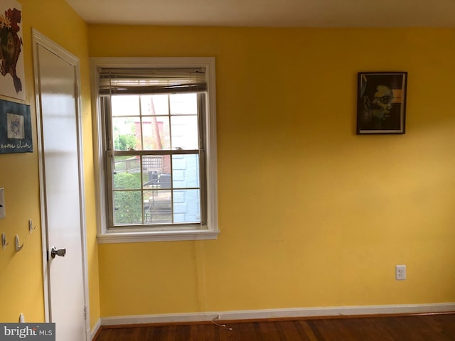 unfurnished room featuring healthy amount of natural light, baseboards, and wood finished floors