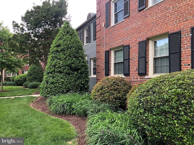 view of side of home featuring brick siding and a lawn