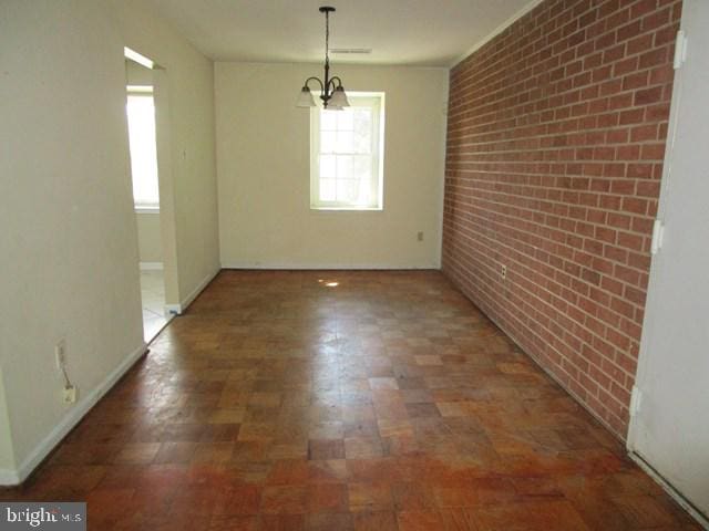 718 Quince Orchard Blvd Unit 718, Gaithersburg, MD 20878 - empty room featuring brick wall, a chandelier, and baseboards