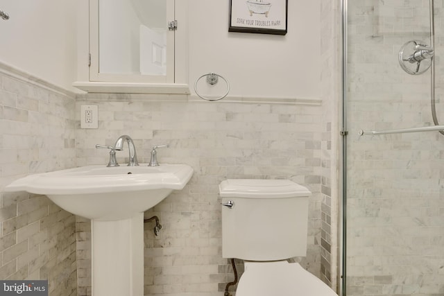 full bath with tile walls, toilet, a sink, a tile shower, and wainscoting