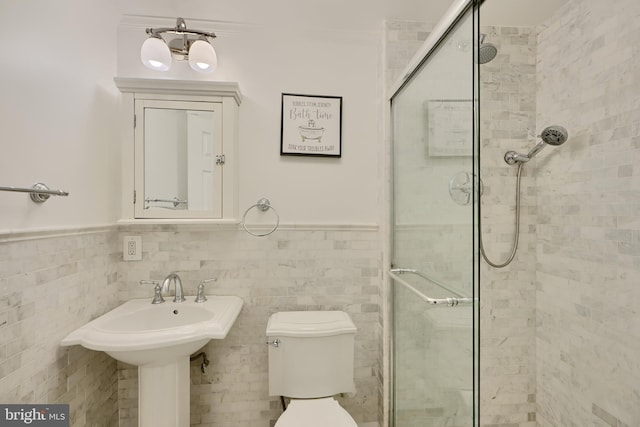 full bathroom with a shower stall, wainscoting, toilet, tile walls, and a sink