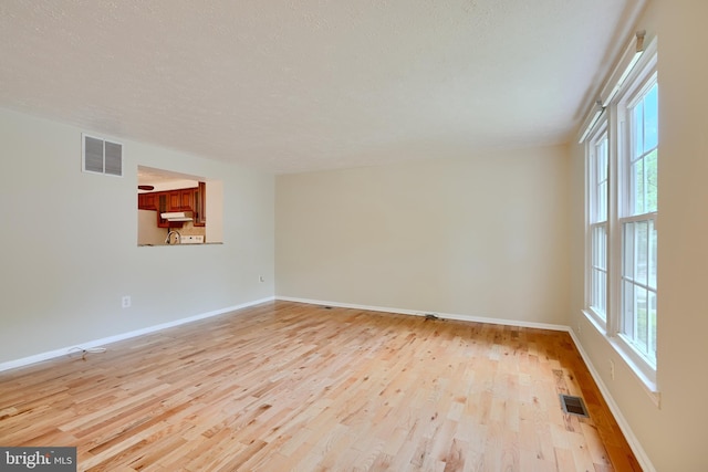 empty room with wood finished floors, baseboards, and a textured ceiling