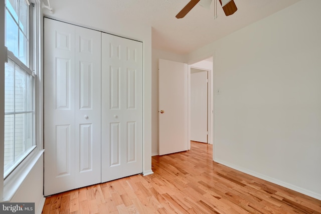 unfurnished bedroom with light wood-style floors, a closet, baseboards, and ceiling fan