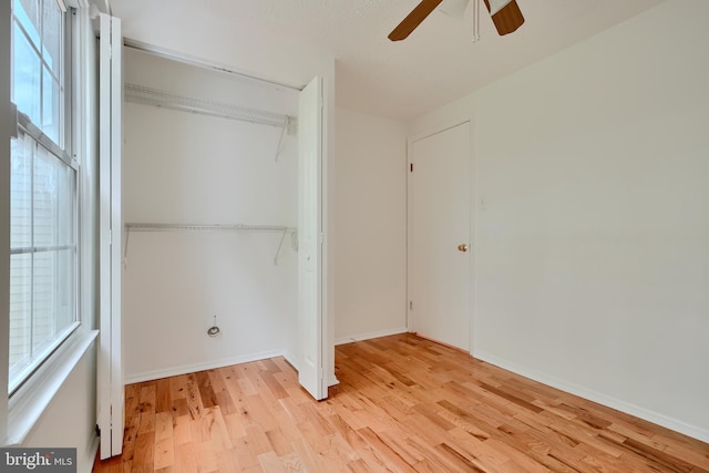 unfurnished bedroom with light wood-style flooring, a closet, a ceiling fan, and baseboards