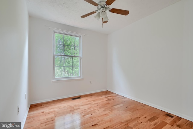 spare room featuring light wood-style floors, a ceiling fan, and baseboards