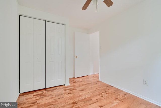 unfurnished bedroom with a closet, light wood finished floors, baseboards, and a ceiling fan