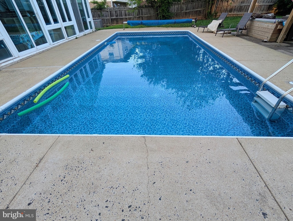 view of swimming pool with a patio and fence
