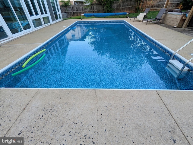 view of swimming pool with a patio and fence