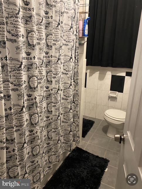 4400 N Franklin St, Philadelphia, PA 19140 - bathroom featuring tile patterned floors, toilet, tile walls, and a shower with curtain