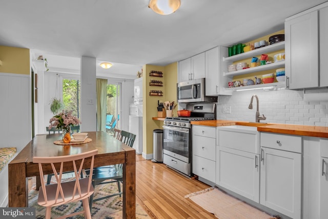 155 E Louther St, Carlisle, PA 17013 - kitchen with stainless steel appliances, butcher block counters, stacked washing machine and dryer, open shelves, and light wood-type flooring