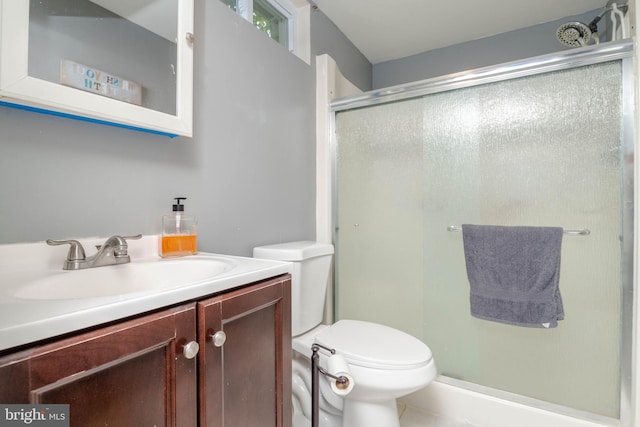 bathroom featuring a shower stall, toilet, and vanity
