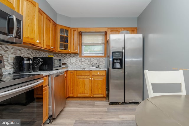 kitchen featuring appliances with stainless steel finishes, a sink, decorative backsplash, and glass insert cabinets