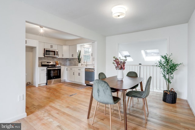 809 N Arch St, Mechanicsburg, PA 17055 - dining room featuring light wood-style flooring, a skylight, and baseboards