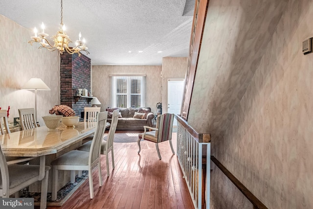dining area featuring a chandelier, a textured ceiling, and hardwood / wood-style flooring