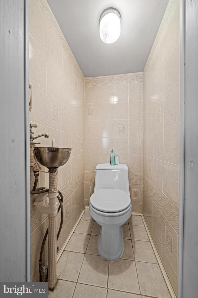 half bath featuring tile walls, tile patterned floors, and toilet