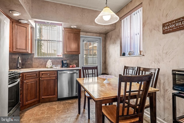 kitchen featuring stainless steel appliances, a sink, plenty of natural light, and light countertops