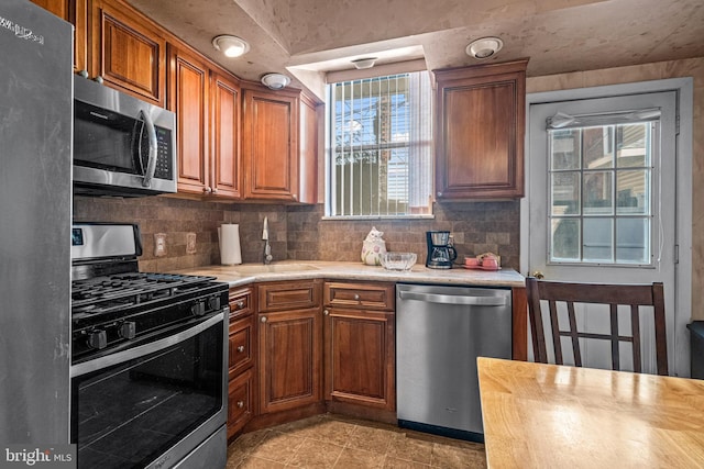 kitchen featuring stainless steel appliances, light countertops, a sink, and backsplash