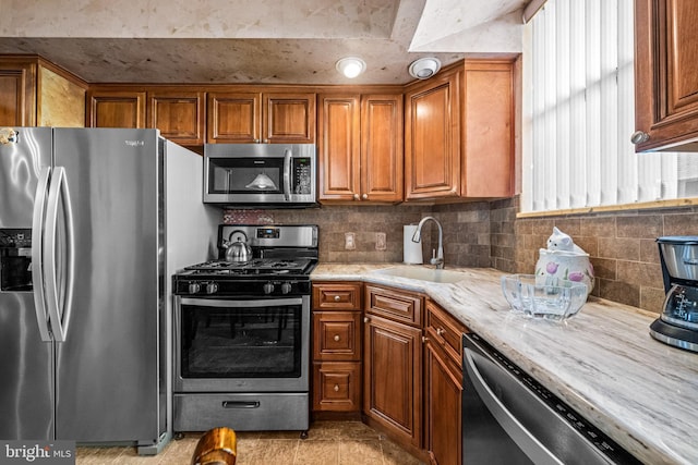 kitchen with appliances with stainless steel finishes, a sink, and brown cabinets