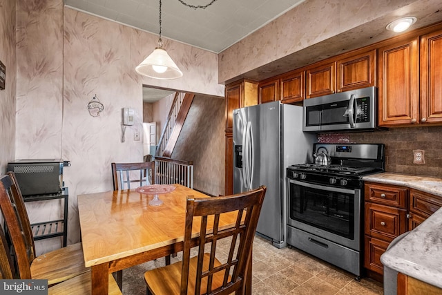 kitchen featuring stainless steel appliances, brown cabinetry, hanging light fixtures, and decorative backsplash