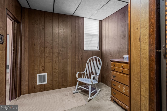 sitting room featuring carpet floors and wood walls