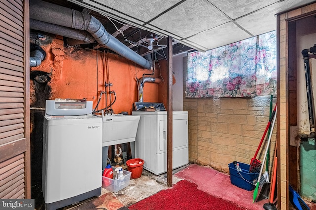 clothes washing area featuring independent washer and dryer and a sink