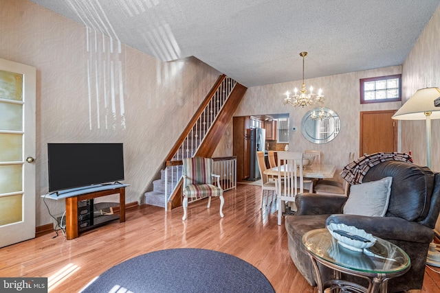 living room featuring stairway, a chandelier, wood finished floors, and a textured ceiling