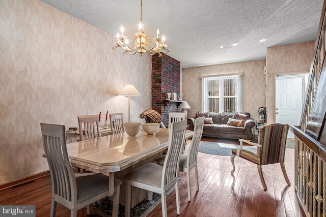 dining room with a textured ceiling, hardwood / wood-style flooring, a chandelier, and baseboards