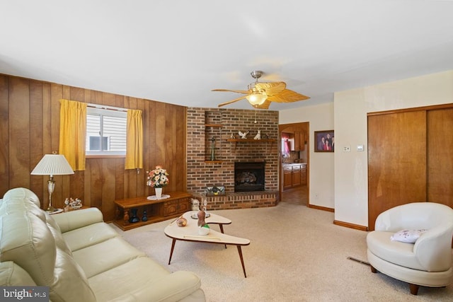 living room with a ceiling fan, carpet flooring, wooden walls, a fireplace, and baseboards