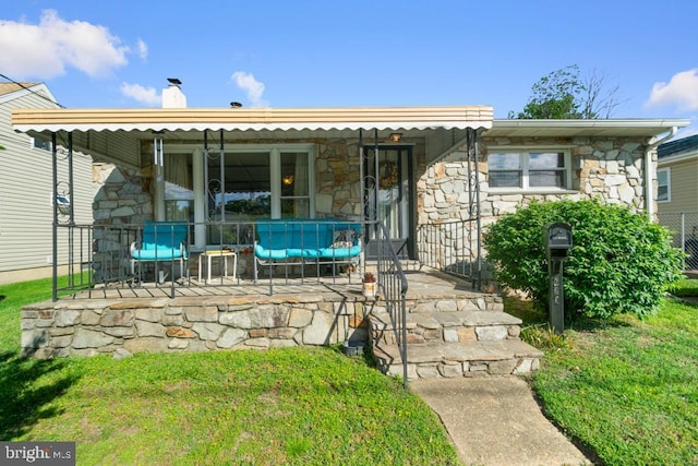 back of property with stone siding and a chimney