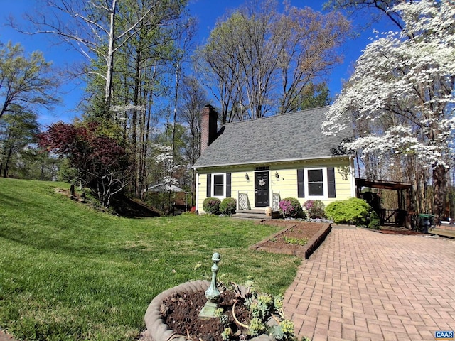 cape cod-style house with a chimney, a front yard, and roof with shingles