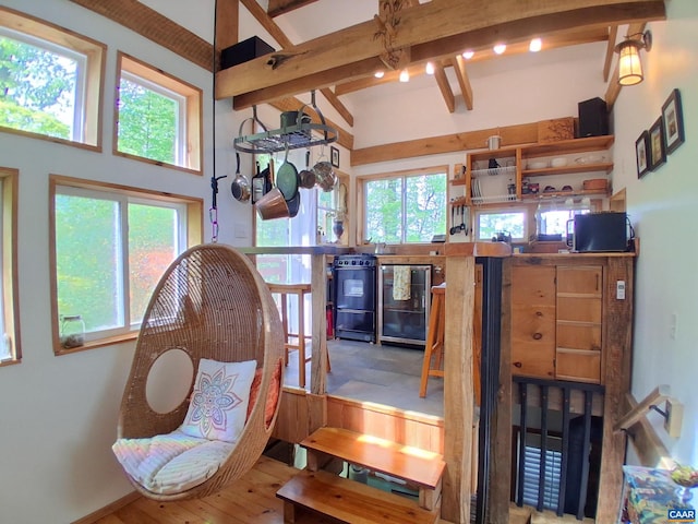 dining space featuring beamed ceiling, beverage cooler, and wood finished floors