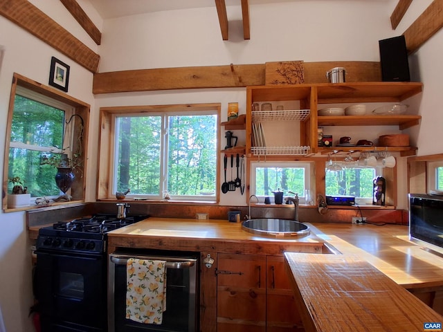 kitchen with black range with gas cooktop, a sink, open shelves, and wood finished floors