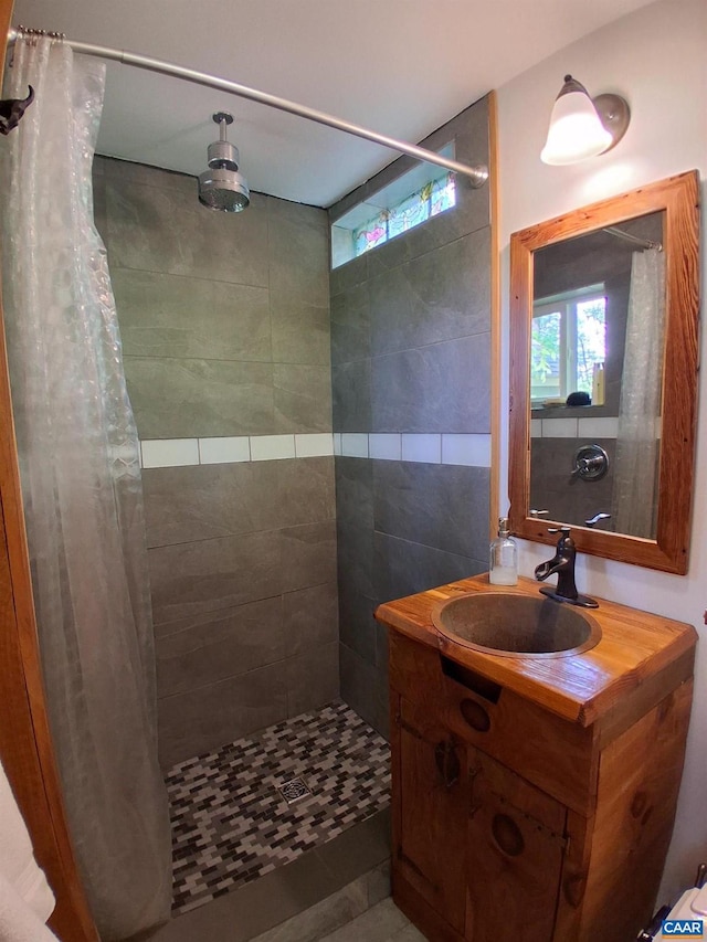 full bath with a tile shower and vanity