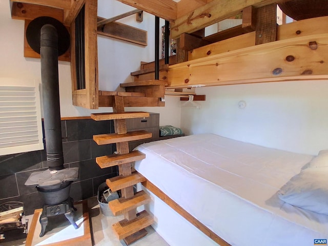 bedroom featuring a wood stove, tile walls, and a wainscoted wall